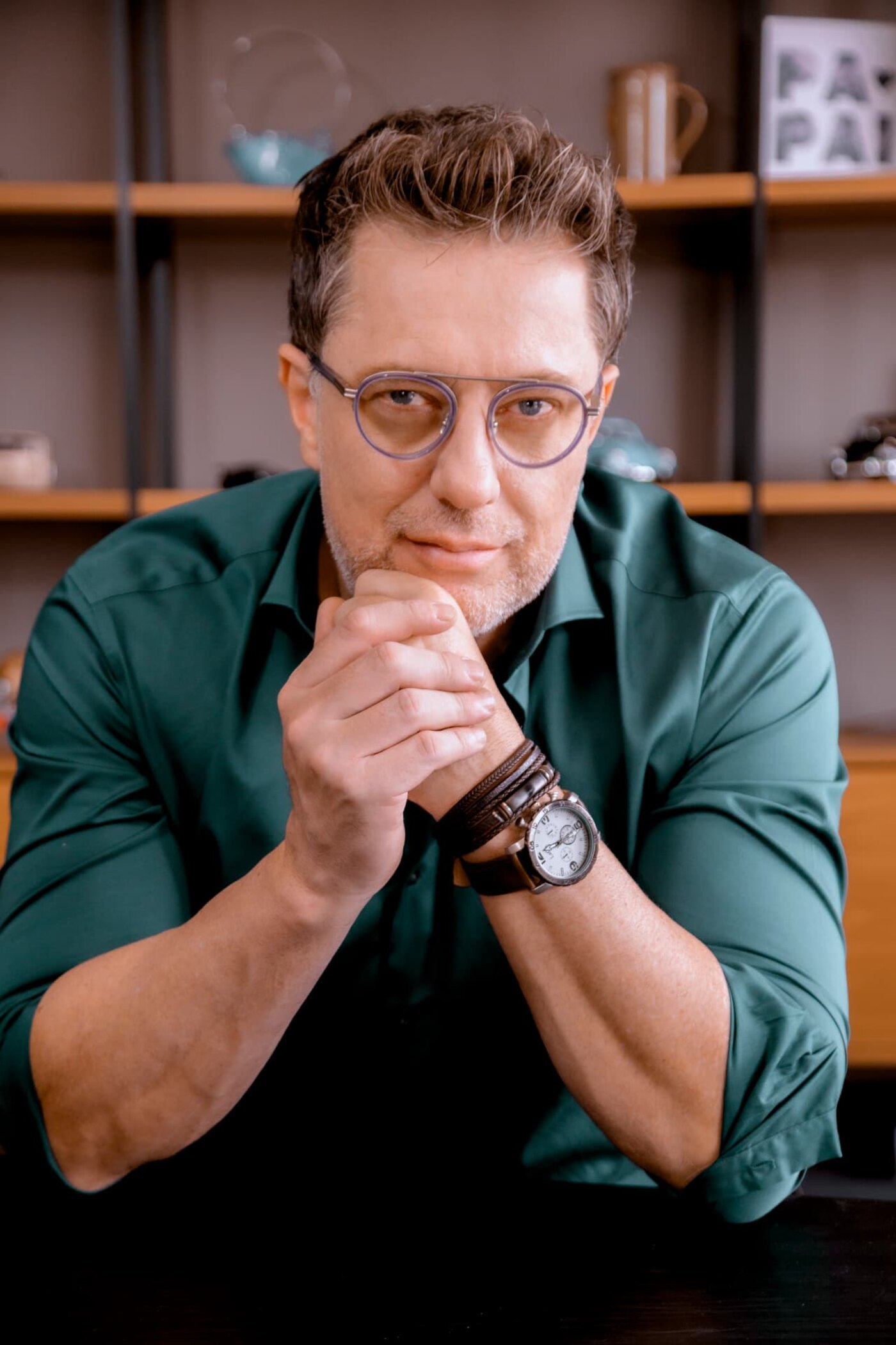 Retrato de Gláucio Gonçalves, arquiteto e founder do IDECOR, de camisa verde profunda com as mãos apoiadas.